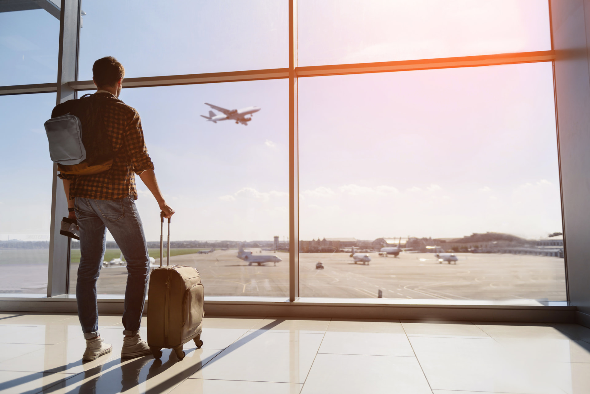Gast mit Koffer und Reiseunterlagen am Terminalfenster